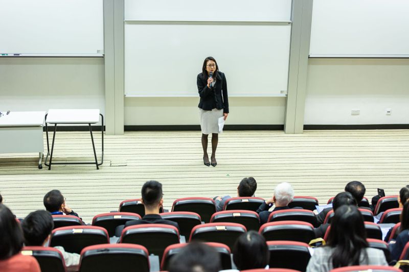 A woman addressing an audience from a conference stage